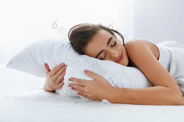 枕头.女人静止的向白色的枕头睡眠采用床