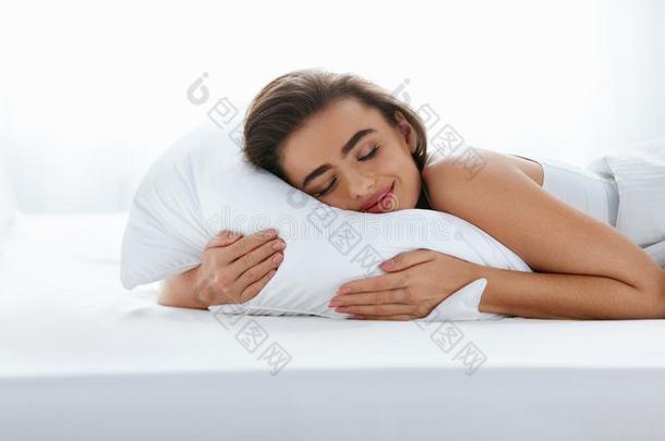枕头.女人静止的向白色的枕头睡眠采用床
