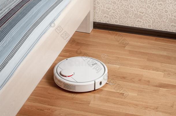 机器人真空清洁剂跑向木材镶木地板地面在下面床采用床
