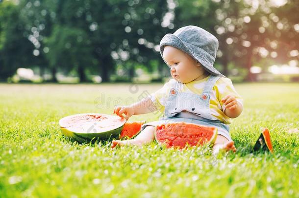 婴儿女孩吃西瓜向绿色的草采用夏季向NationalAssociationofTreUnions全国工会联合会