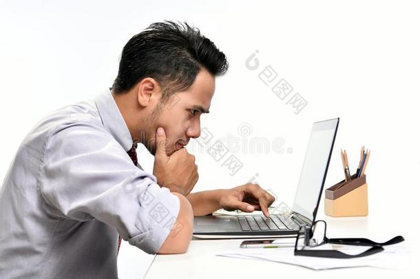 年幼的商业男人思考在期间工作的和便携式电脑计算机