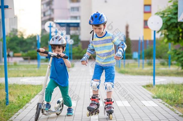 两个小孩男孩向滚筒溜冰鞋和他的<strong>兄弟兄弟</strong>向小型摩托车