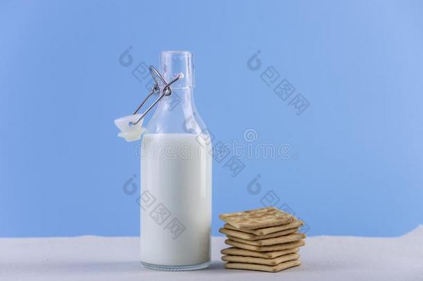 玻璃瓶子关于新鲜的奶和甜饼干向蓝色背景.颜色