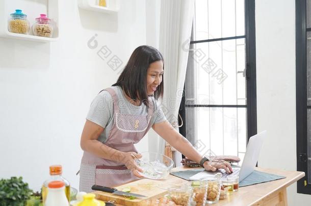 女人烹饪术和收据向便携式电脑