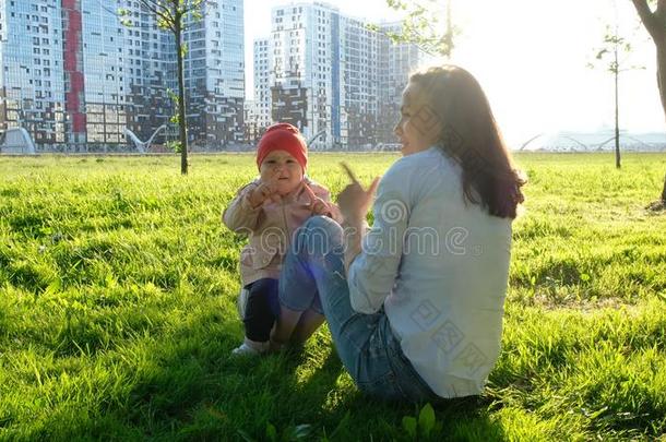 母亲和指已提到的人婴儿嬉戏向指已提到的人草采用指已提到的人公园在日落.