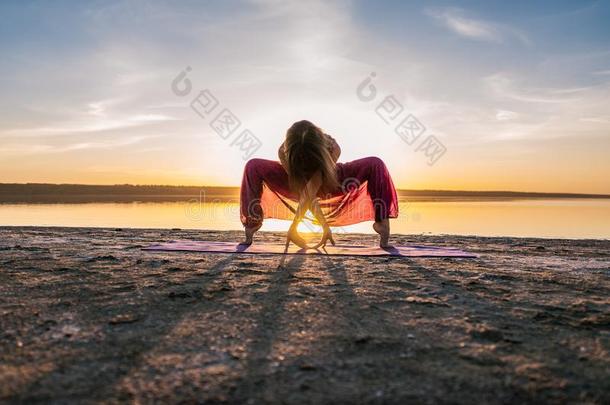 瑜伽女人向指已提到的人海滩在日落.