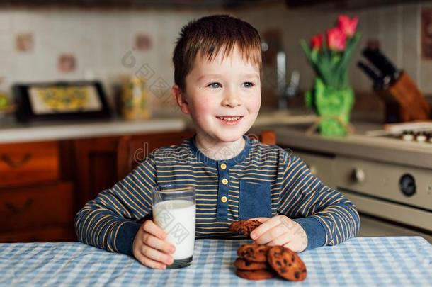 一小的男孩饮料奶和食物甜饼干采用指已提到的人厨房采用指已提到的人