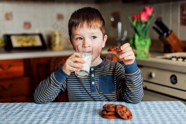 一小的男孩饮料奶和食物甜饼干采用指已提到的人厨房采用指已提到的人