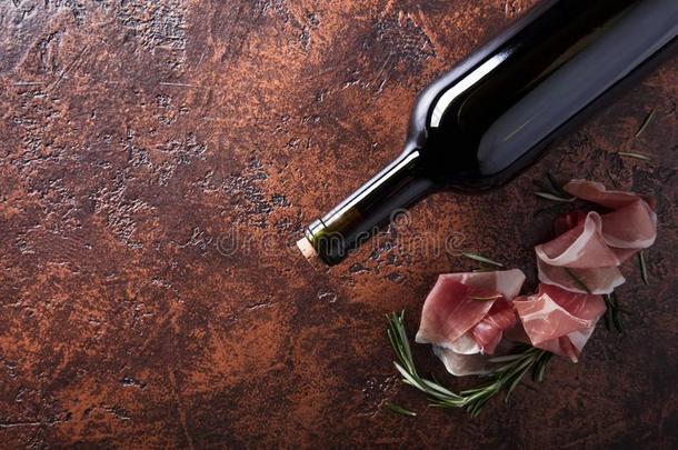 意大利熏火腿和迷迭香和瓶子关于红色的葡萄酒.
