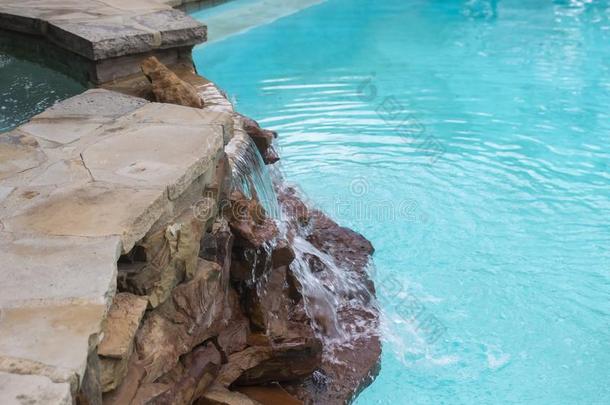 瀑布越过岩石从热的澡盆向高高的水平下向游泳