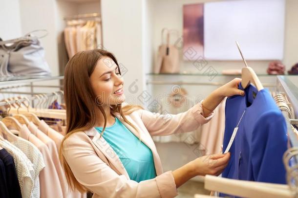 幸福的女人挑选衣服在衣服商店