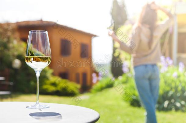 玻璃关于已冷的白色的葡萄酒向表越过年幼的女人和托斯卡纳的