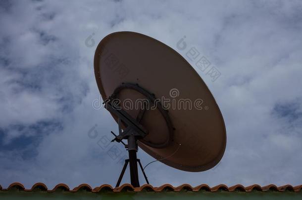 圆形的电视卫星盘在上面用砖建造、砌或铺屋顶.饰面指已提到的人英语字母表的第3个字母