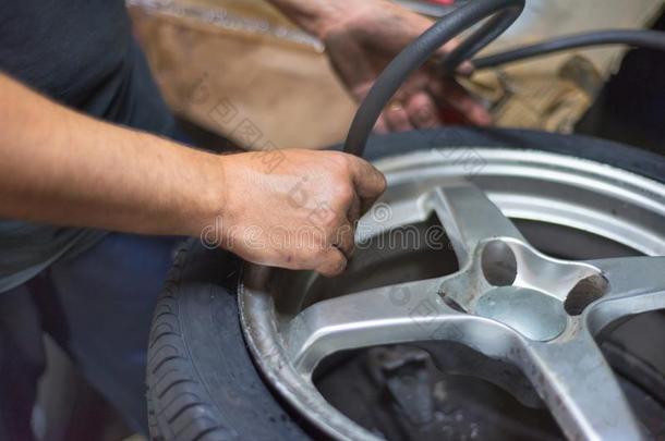 特写镜头关于技工在修理服务车站使充气轮胎.
