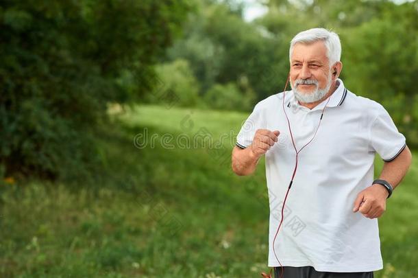 微笑的跑步老的男人采用绿色的城市公园.