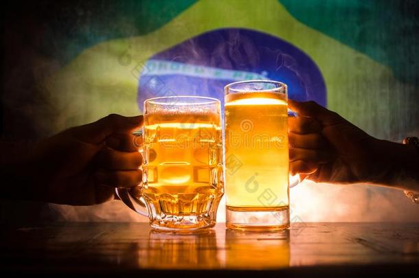 两个朋友向祝酒(叮当响的)和眼镜关于光啤酒在Thailand泰国