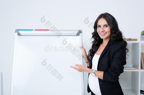 幸福的怀孕的女商人弄尖在空白的白色书写板和int.看