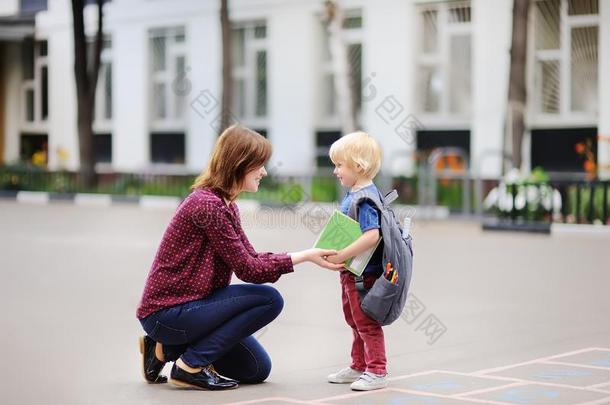 背向学校观念.小的学生和他的年幼的母亲.冷杉