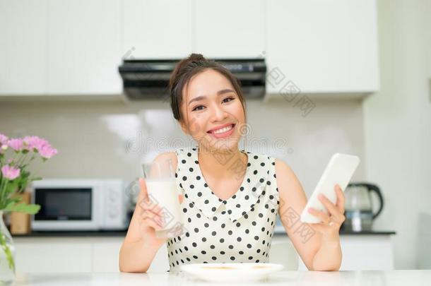 年幼的微笑的女人吃甜饼干和微笑的,使用智能手机