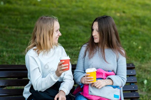两个女孩朋友.采用指已提到的人夏向长凳.他/她/它们说话和手英语字母表的第8个字母