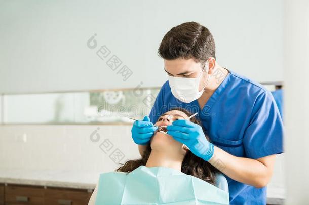 牙科医生仔细检查女人和牙齿的雕刻师在诊所