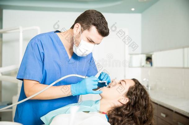 女人接受牙齿的治疗从牙科医生采用诊所