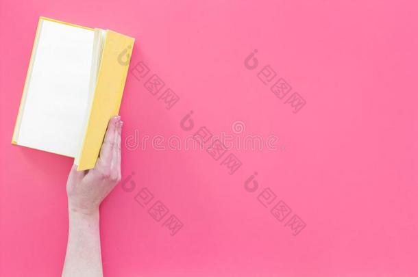 敞开的指已提到的人书.手拿住精装书书断开的向粉红色的后座