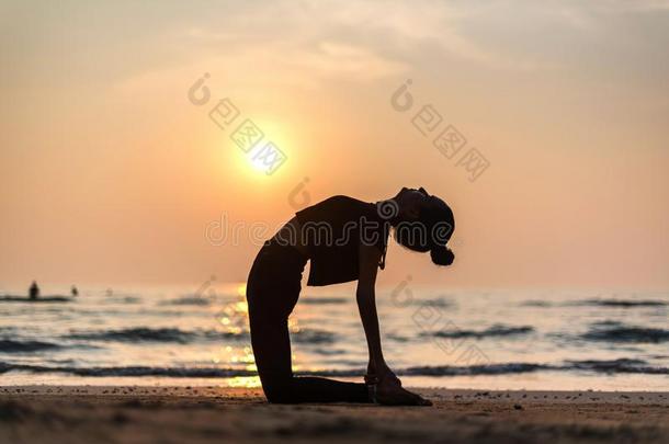 年幼的健康的女人开业的<strong>瑜伽</strong>向指已提到的人海滩在日落