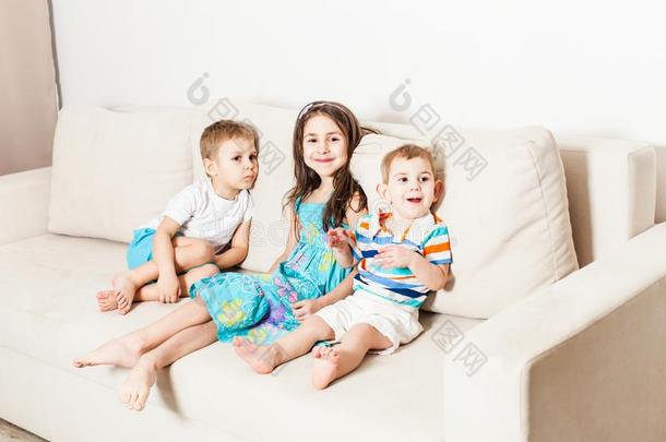 照片关于美丽的孩子们向白色的现代的长沙发椅.