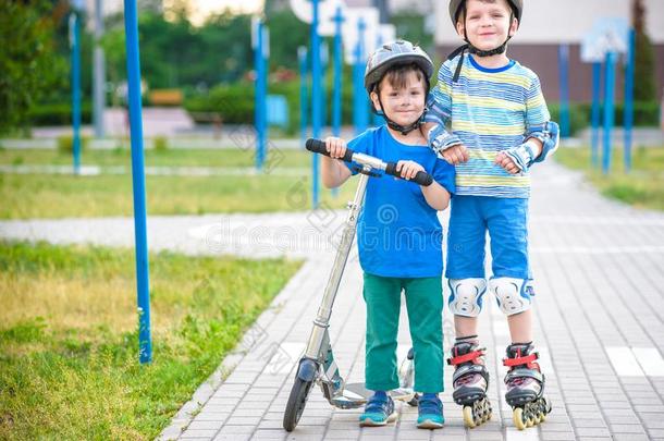 两个小孩男孩向滚筒溜冰鞋和他的兄弟兄弟向小型摩托车