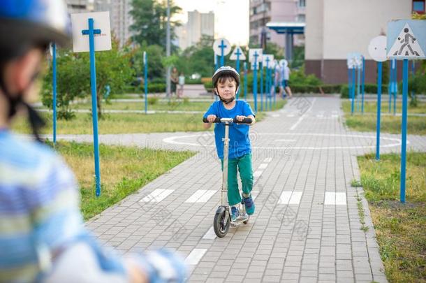 两个小孩男孩向滚筒溜冰鞋和他的兄弟兄弟向小型摩托车