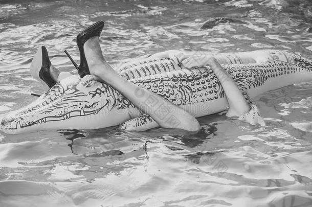 夏休息.流行的女人使摆姿势.鞋子从鳄鱼露天人工水渠