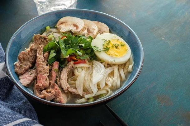 亚洲人拉面汤和牛肉,鸡蛋,韭黃和蘑菇采用碗.
