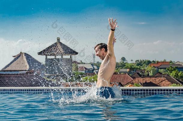 很幸福的,苗条的年幼的微笑的男人,用于跳跃的出局关于水池水