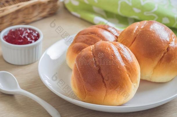 圆形的圆形的小面包或点心,面包名册向白色的盘子和草莓果酱