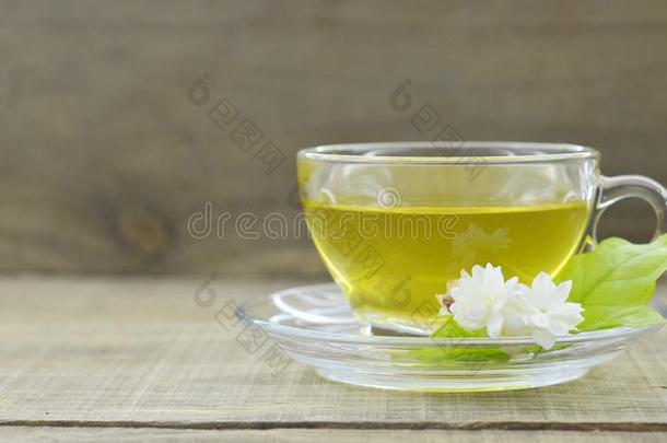 玻璃杯子和茶水和茉莉花向木制的表