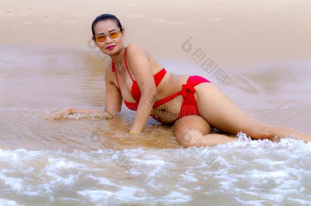 女人大的身体和<strong>红色</strong>的<strong>比基尼</strong>式游泳衣幸福的波浪向海滩