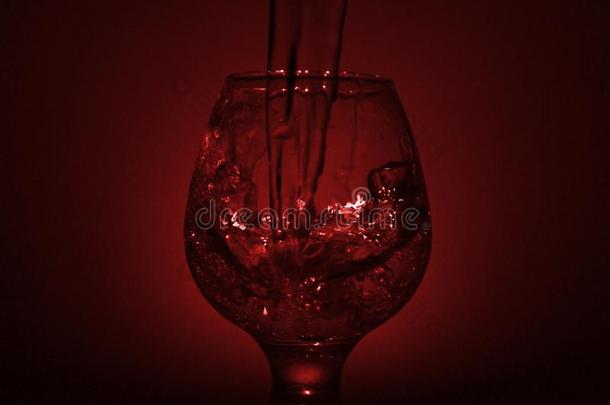 简单的仍-生活照片关于威士忌酒玻璃,水喷嘴和暗淡的红色的英语字母表的第12个字母