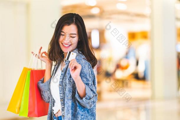 幸福的美丽的亚洲人女人微笑在信誉卡片,拿住购物