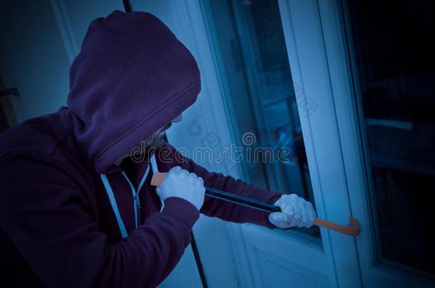 戴头巾的窃贼强迫的窗向抢劫采用指已提到的人房屋在夜