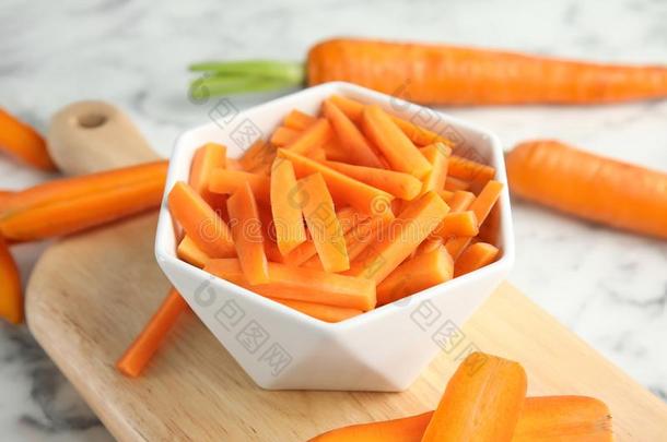 碗和将切开成熟的胡萝卜向板