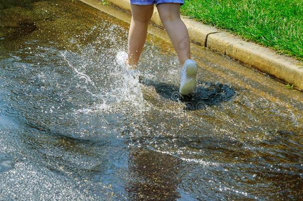 小孩女孩跑步和用于跳跃的采用水坑后的ra采用采用夏