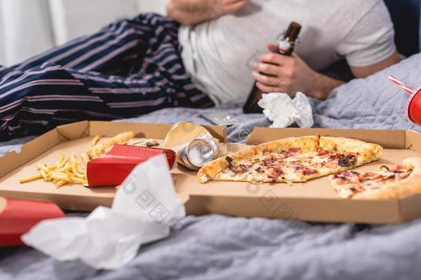 裁切不正的影像关于喜孤独者吃意大利薄饼和啤酒向床