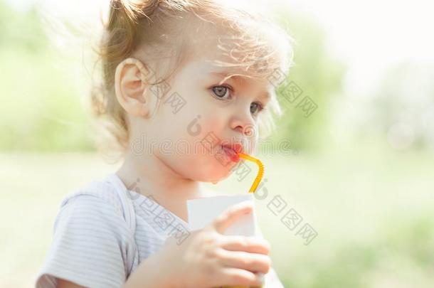 和煦的：照到阳光的肖像关于一小的小孩喝饮料从一str一w果汁向