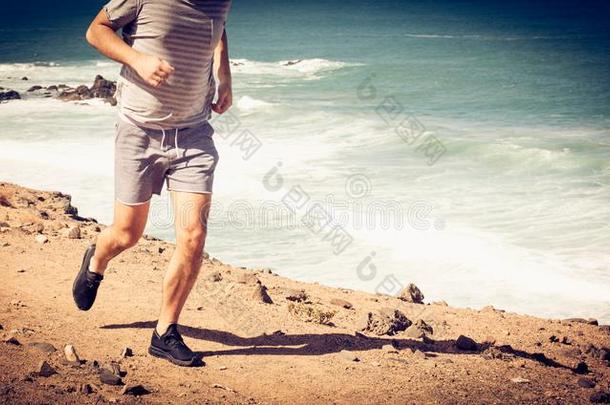 健康的男人慢跑向海滩.