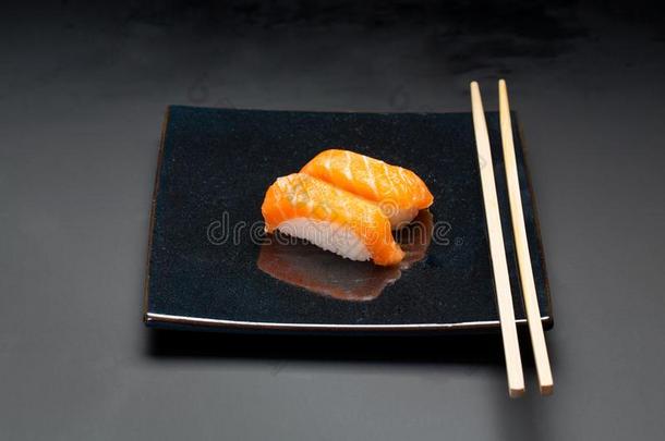 黑的盘子和鲑鱼寿司和筷子