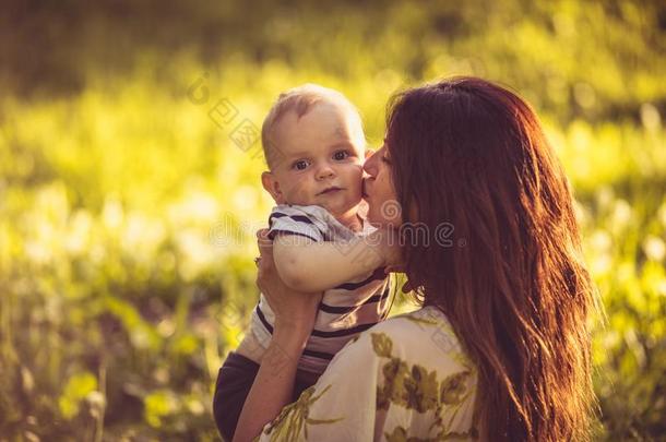肖像关于年幼的母亲和她婴儿男孩,时间为吻.
