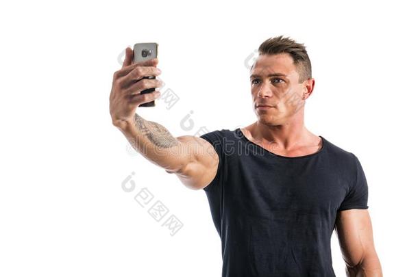 英俊的肌肉的年幼的男人迷人的自拍照和细胞电话