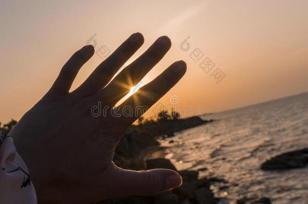 上升的太阳微量发光通过手指在海岸在太阳rise时间