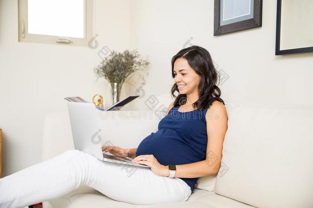 怀孕的女士使用便携式电脑在的时候她空闲时间时间